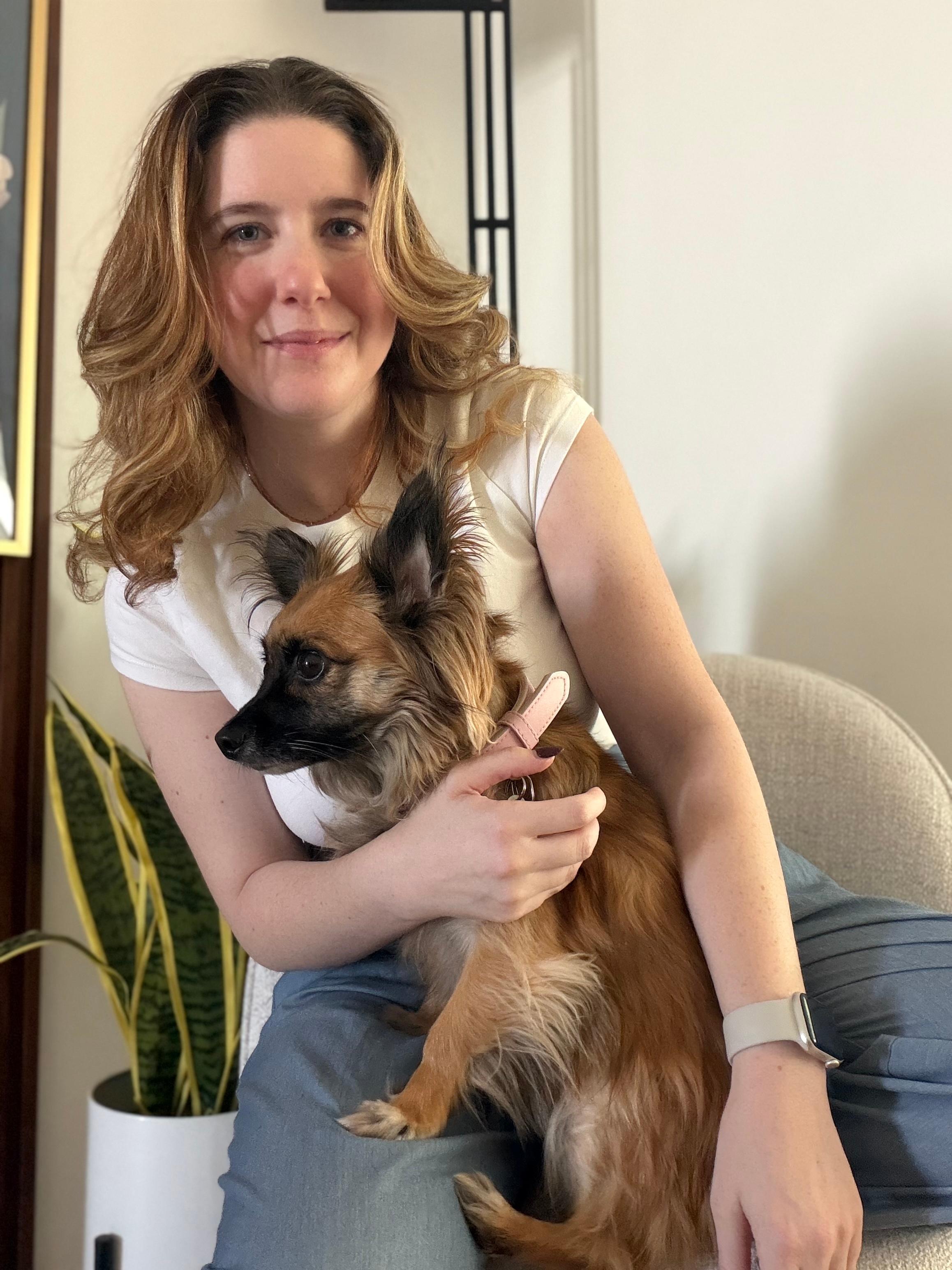 Current president Eliana sitting on a chair at home with her dog Phineas on her lap
